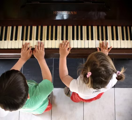 Two small kids learning and playing a piano